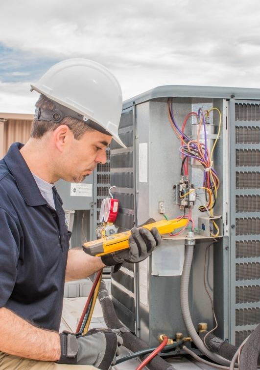 HVAC technician servicing an air conditioning unit in Kearns, Utah